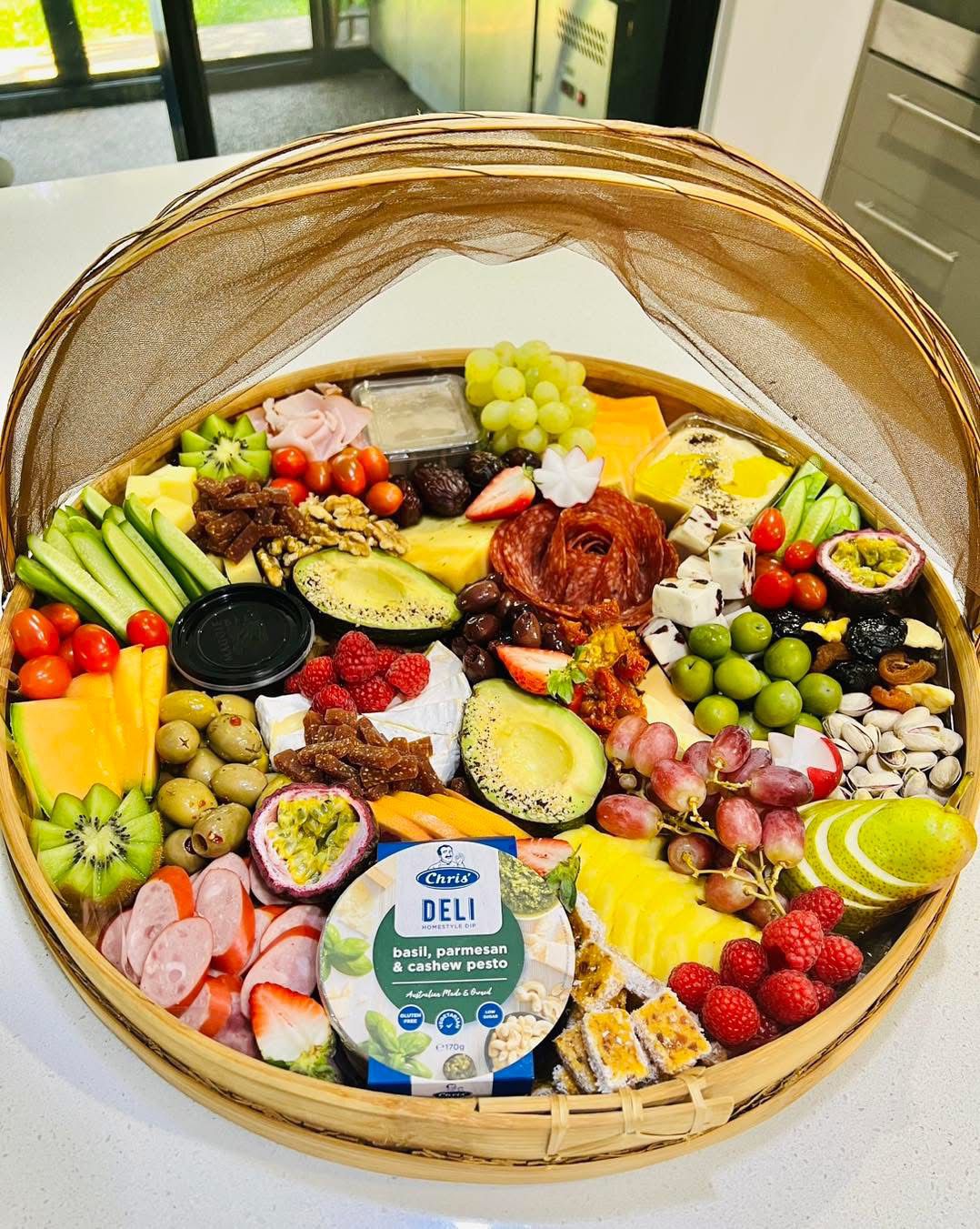 A gigantic round grazing platter overflowing with cured meats, cheeses, fresh fruit, dips, olives and nuts